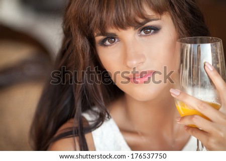Beautiful young woman drinking orange juice at summer cafe lifestyle, closeup portrait of happy woman face with drink. Woman in restaurant in morning. Summer vacation.