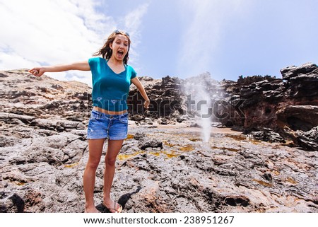 Young Attractive Woman Next to a waterspout with arms reached out in excitement