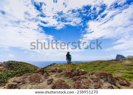 Woman Standing Wide Angle on rocky ledge in front of blue sky and ocean