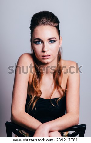 Studio Portrait of Young Attractive Woman sitting backwards on chair slight smile