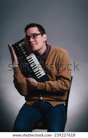 cheesy portrait of a man smiling silly caressing his piano keyboard
