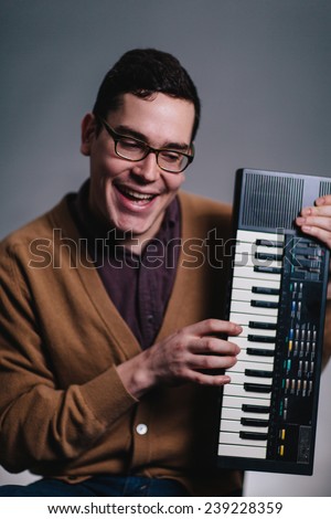 cheesy portrait of a man smiling silly at his piano keyboard