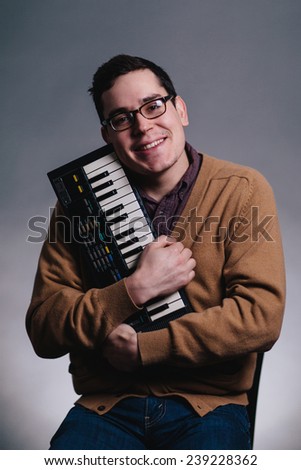 cheesy portrait of a man smiling silly hugging his piano keyboard