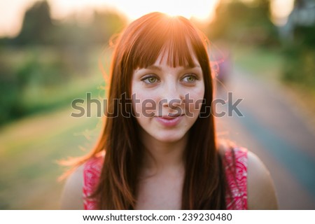 portrait of beautiful young female sun behind head looking off camera slight smile