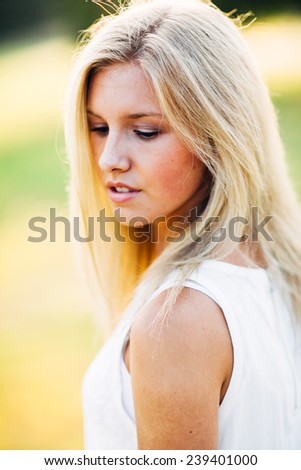 portrait of beautiful young blonde woman in field side profile looking down