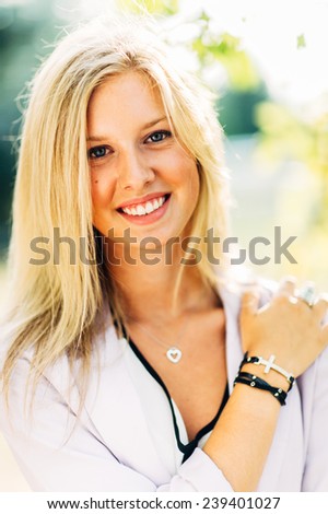 portrait of beautiful young blonde woman holding shoulder smiling