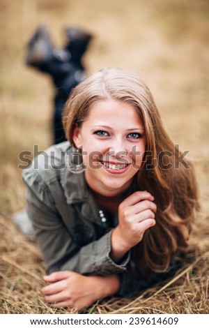 Attractive Young Blond Woman laying in straw feet up smiling