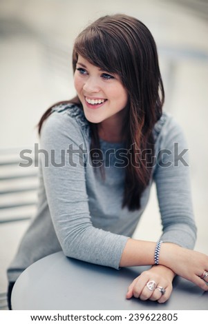 Attractive Young Woman Sitting outside smiling away from camera