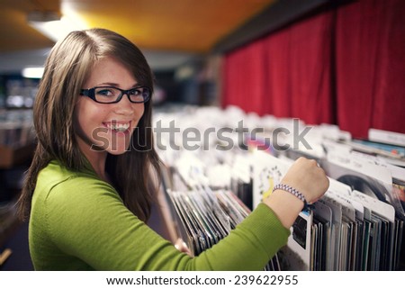 Attractive Young Woman Smiling While Looking at Records in a music store