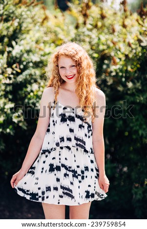 attractive young red head sun directly overhead playing with dress