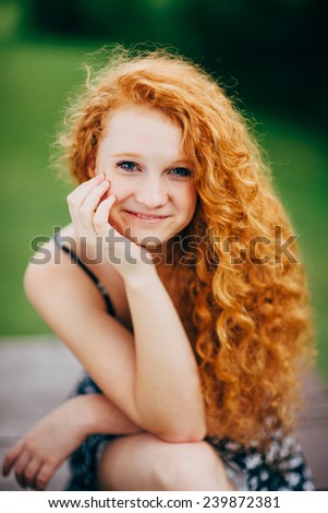 Attractive Young Female Redhead, smiling, hand under chin, vertical