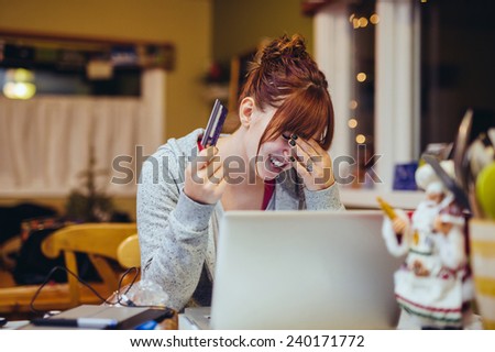 Young Woman at Computer stressed with a credit card hand on forehead