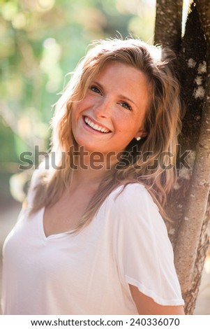 Beautiful Blonde Young Woman leaning on tree zoom vertical laugh