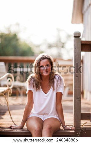 Beautiful Blonde Young Woman sitting on deck slight smile