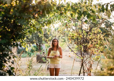 Beautiful Blonde Young Woman standing underneath trees wide shot