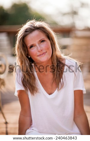 Beautiful Blonde Young Woman sitting on deck slight smile variation