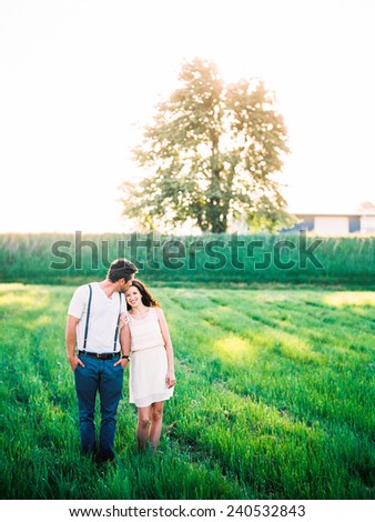 Attractive Young Couple standing in a field guy kissing forehead, girl smiling