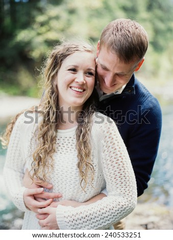 Attractive Young Blond Couple man hugging from behind laughing and smiling
