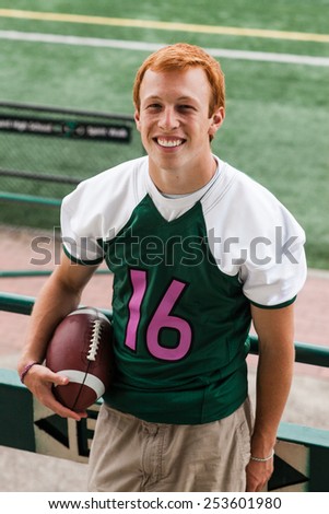 Athletic Attractive Young Male Outside at bleachers holding football in football #16 jersey