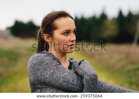 young adult woman stretching in country on cloudy day