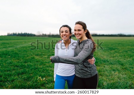 Young Adult Female Runners Arms Around each other smiling in country