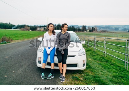 Young Adult Females resting on car after run