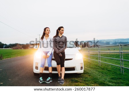 Young Adult Females sitting on car after run to rest