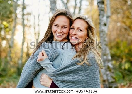 beautiful mom and daughter sharing a blanket in the forest smiling