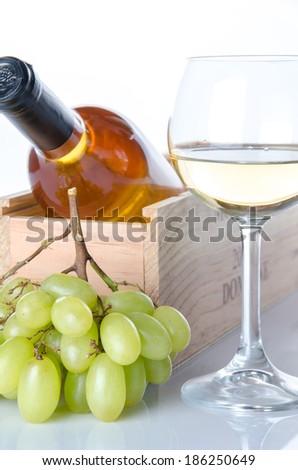 Bottles of wine in a wooden box with a glass of wine and white grapes, isolated on white