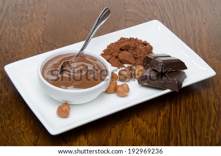 Composition of chocolate hazelnut spread, hazelnuts, chocolate and cocoa on a wooden background
