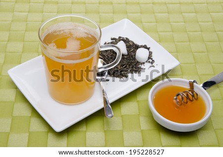 Cup of tea with honey, on a green table mat