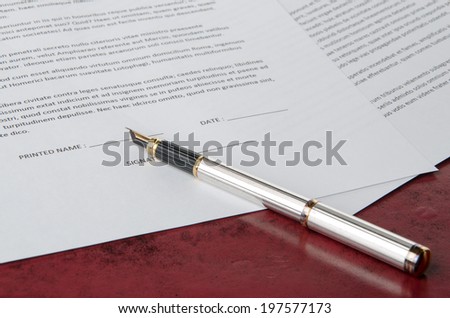 Pen prepared to sign a paper on a red leather desk pad