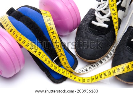 Pink dumbbell, ankle weights and fitness shoes with a tape measure, isolated on white