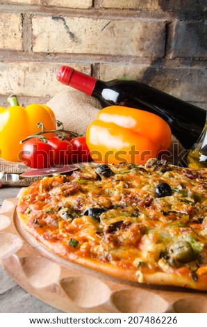 Composition with a pizza, wine and some ingredients on a firebricks background