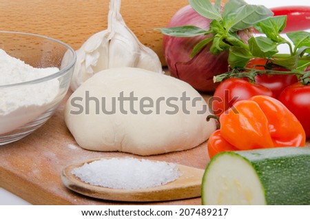 Different ingredients to make a pizza on a wooden board