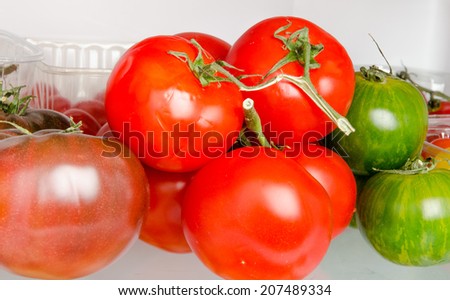 Red, green and purple tomatoes inside a refrigerator