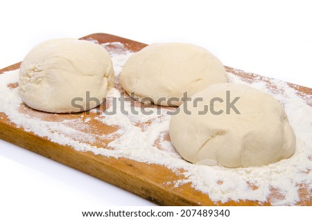 Three balls of pizza dough on a wooden board, isolated on white