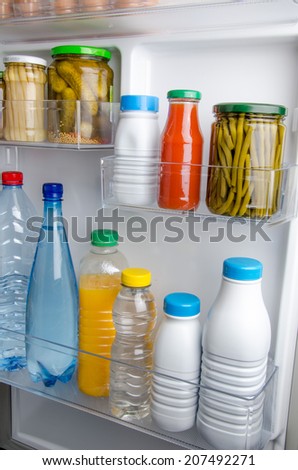 Bottles and food cans within the door of a refrigerator