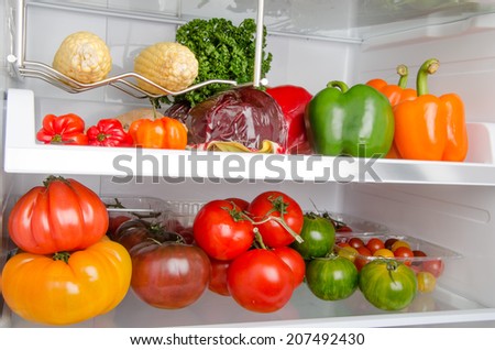 Peppers, tomatoes and other different vegetables inside a refrigerator