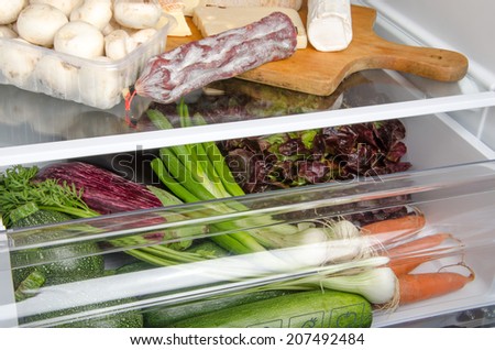 Cheese, sausage, mushrooms and different vegetables inside a refrigerator