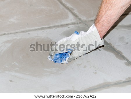 Laying floor tiles, tiler cleaning tiles after filling up joints