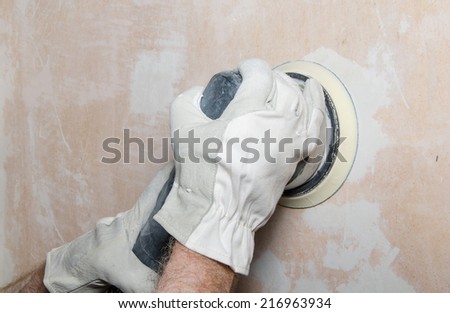 Room repair,sanding of a wall with a power sander