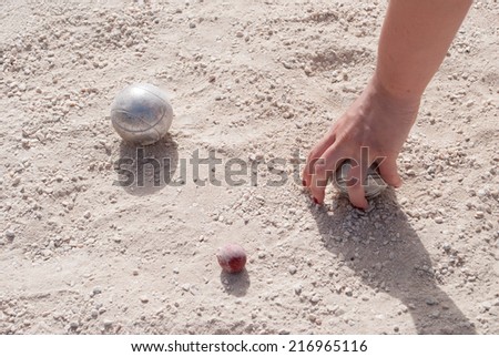 Human\'s hand taking a petanque ball on the ground