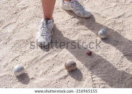 Human\'s foots in front of petanque balls and a small red jack
