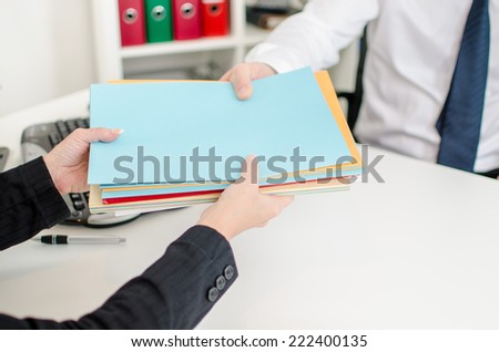 Secretary putting files in the hand of a businessman at the office