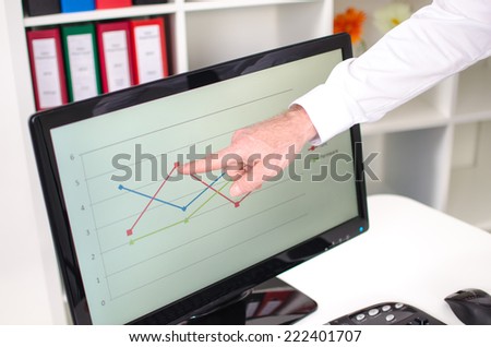 Businessman showing a graph on the screen with his index finger