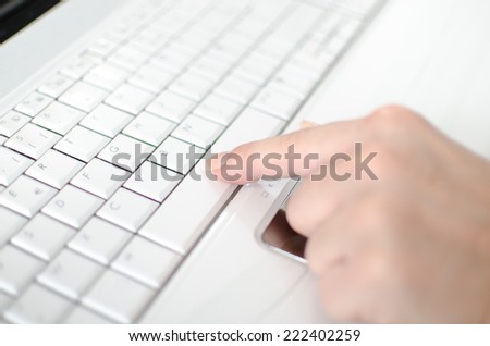 Female index finger typing on a white keyboard, closeup