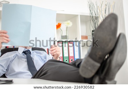 Relaxed businessman analyzing a document at office