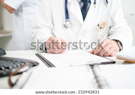 Doctor signing a medical report in his office