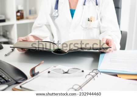 Female doctor reading a medical book at her desk
